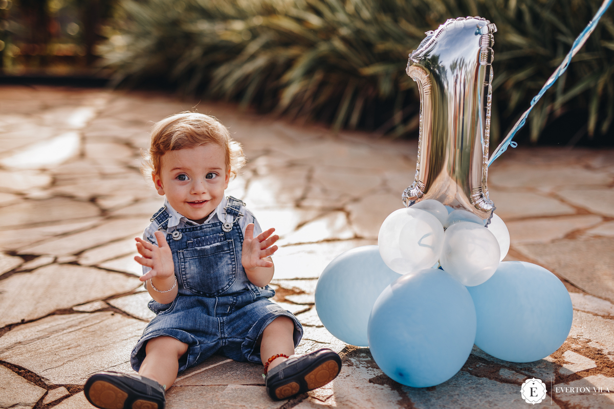pequeno théo sentado brincando em sessão de fotos