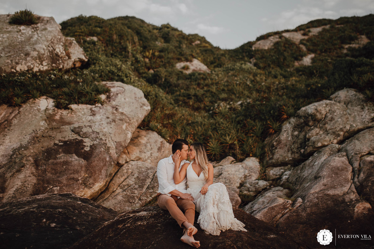 noivo e noiva sentados em pedra em praia ilha do mel no paraná