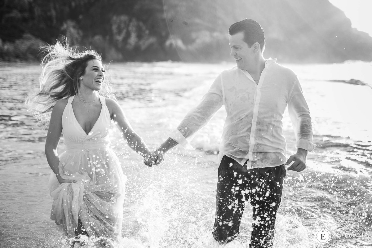 casal de noivos se divertindo e correndo pela água em sessão de fotos