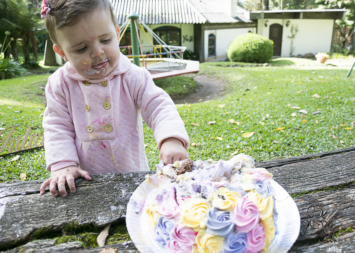 bebê é clicado por by Eli Matos com as  mãos em um bolo colorido