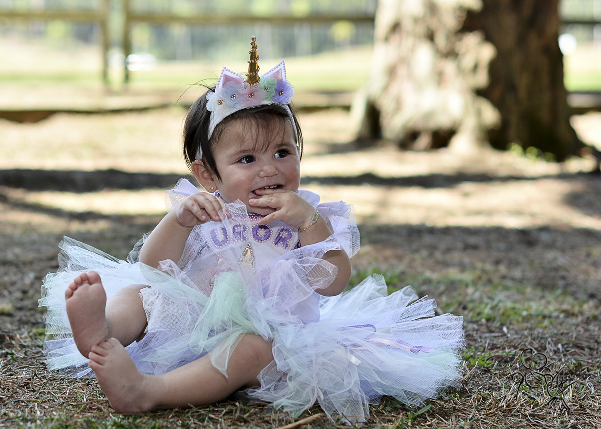 Criança de um ano sorrindo e segurando sua saia tutu,  by Eli Matos registrou
