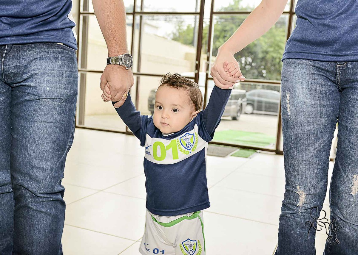 Bebê de um ano caminha com seus pais segurando em duas mãos, clique de by  Eli Matos