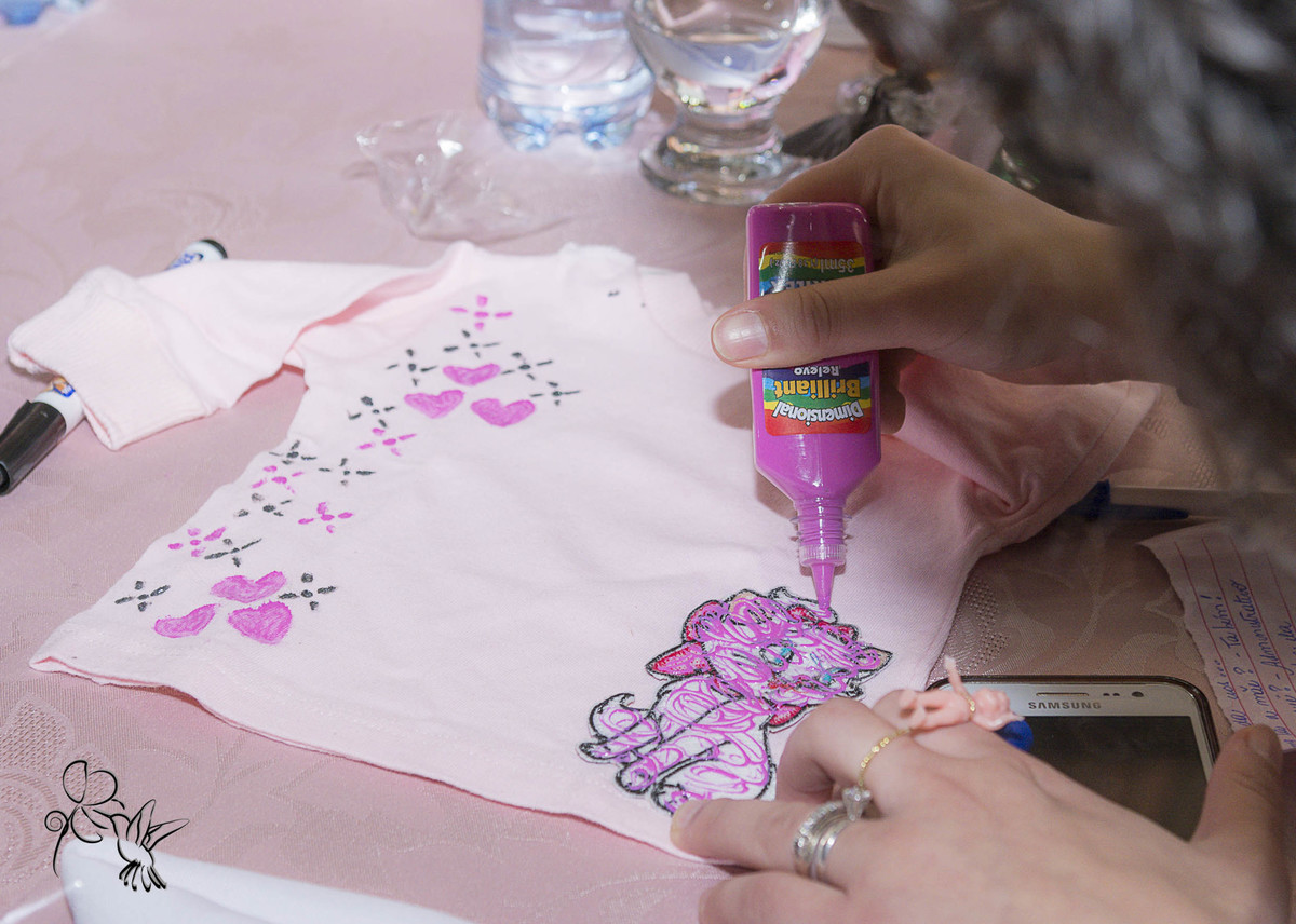 pessoa colando decalques em camiseta rosinha para a Cecilia, by Eli Matos capta o momento