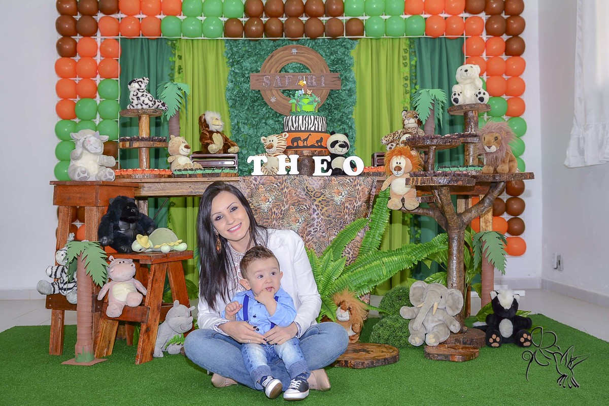 Mãe e bebê sentados e sorrindo  em frente ao painel principal da decoração safári, clique de by Eli Matos