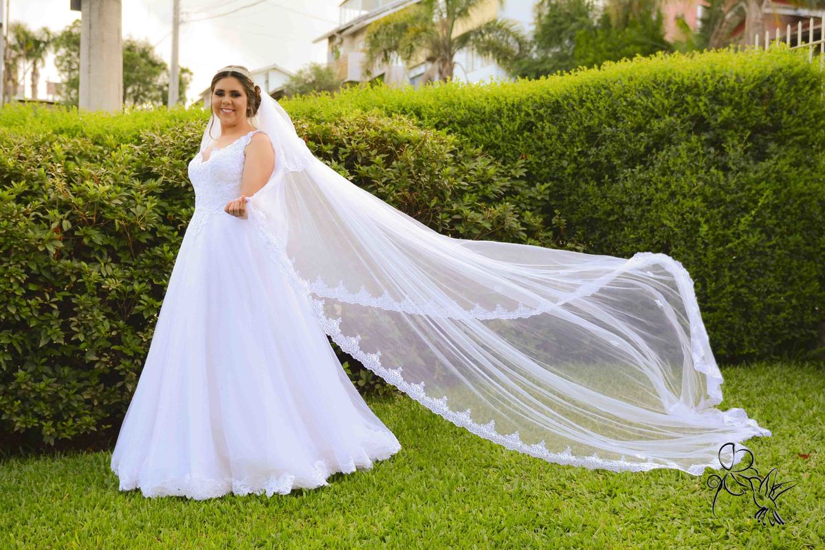 Noiva toda de branco próxima a uma cerca verde, clique de by Eli Matos