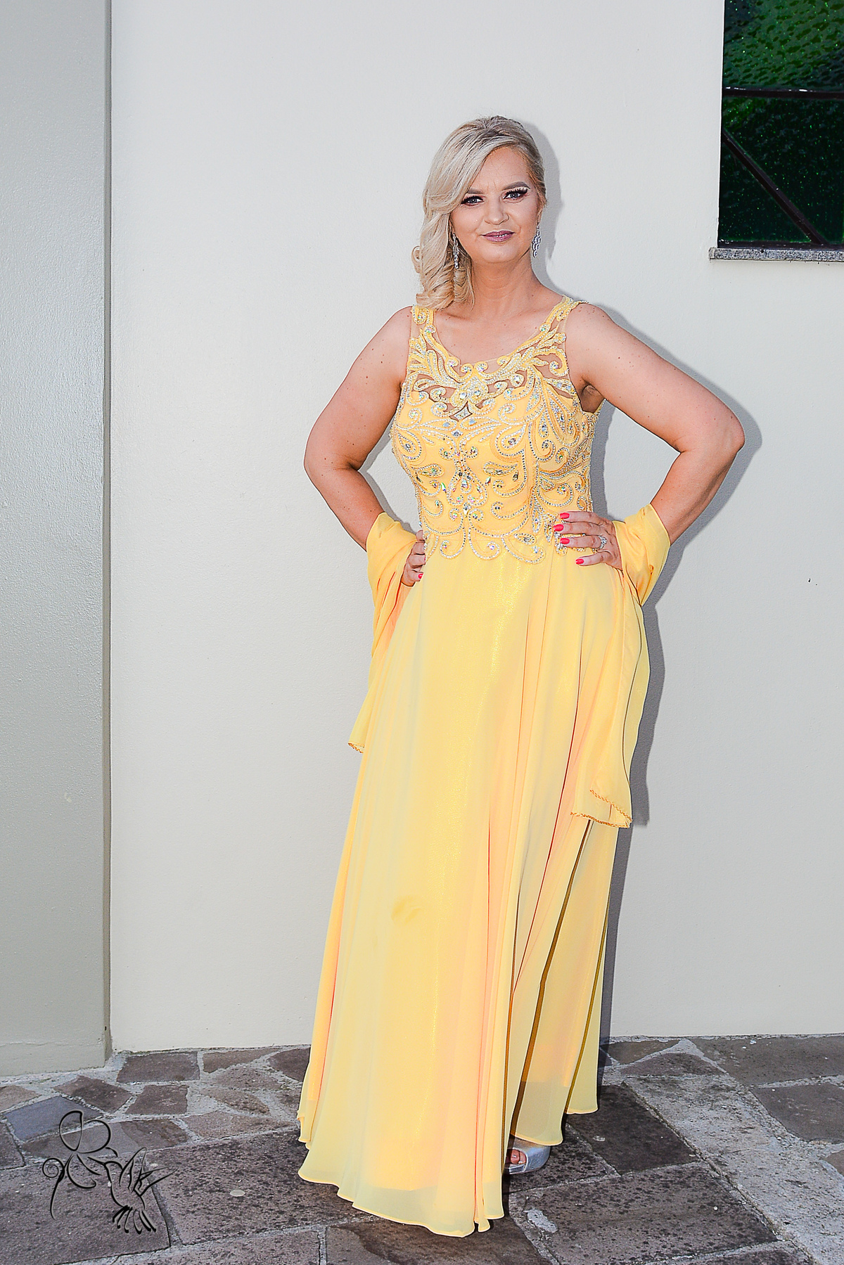 Mulher de 50 anos com vestido de festa amarelo ouro com rendas e exarpe, no clique de by Eli Matos