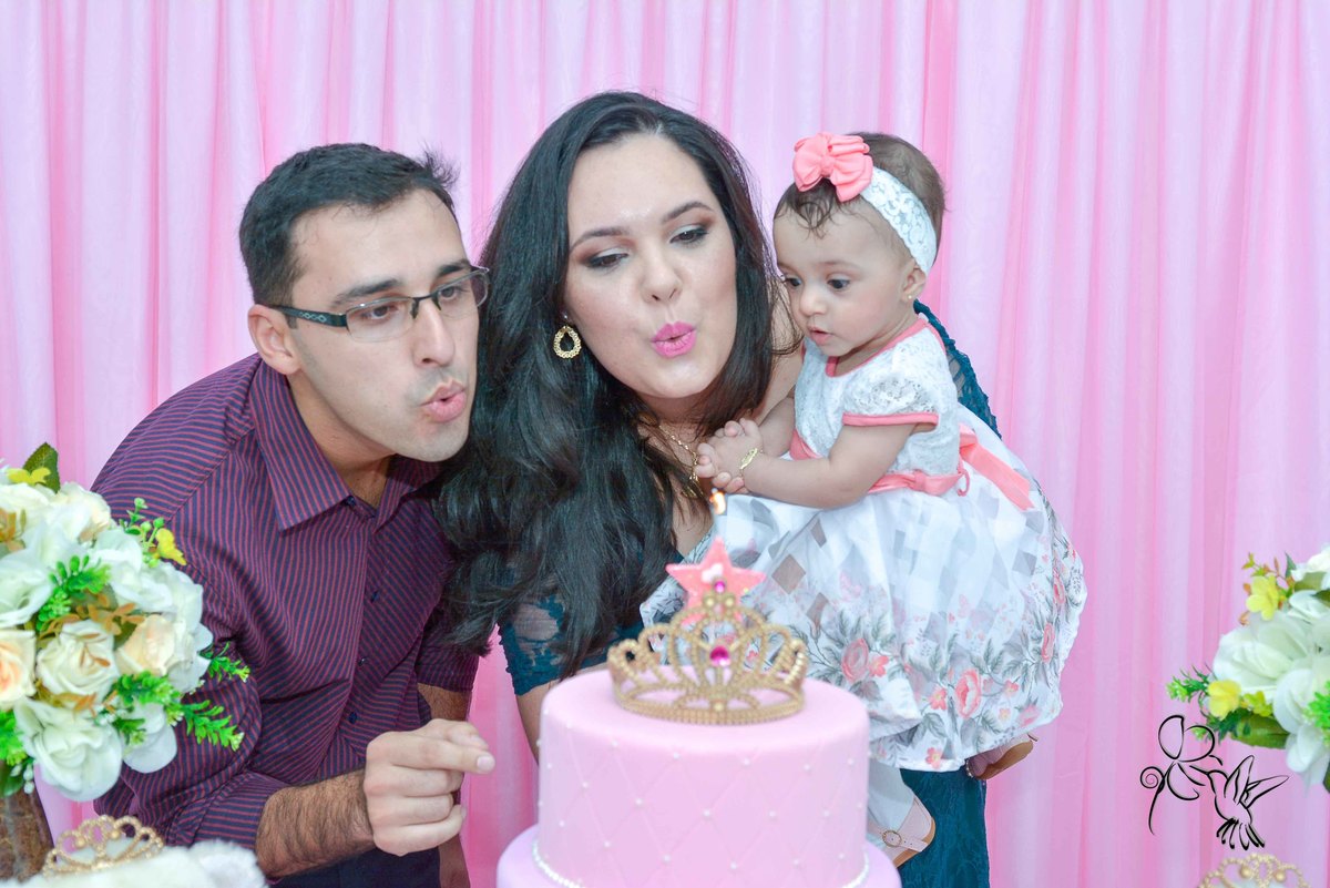 Cecilia e seus pais sopram a velinha de um aninho, em sua festa com decoração em rosa e branco, no clique de by Eli Matos