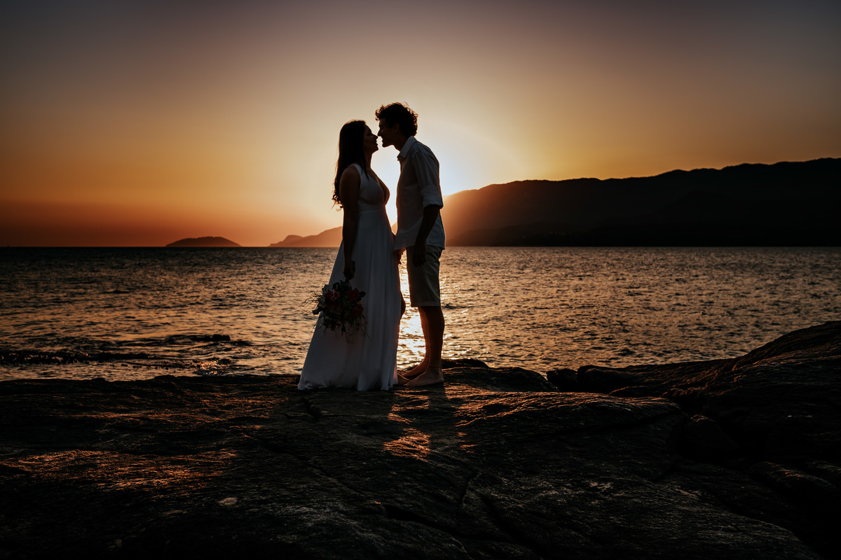 Ensaio Pré-wedding em Ilhabela, noivos na pedra da praia, por do sol, final de tarde.