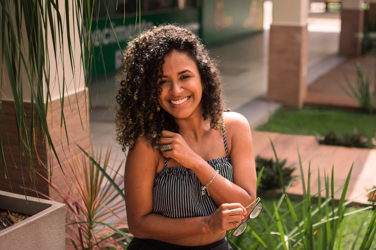 Ensaio fotográfico da Natalia sentada com mão no ombro no Shopping Teixeira Mall na cidade de Teixeira de Freitas - BA