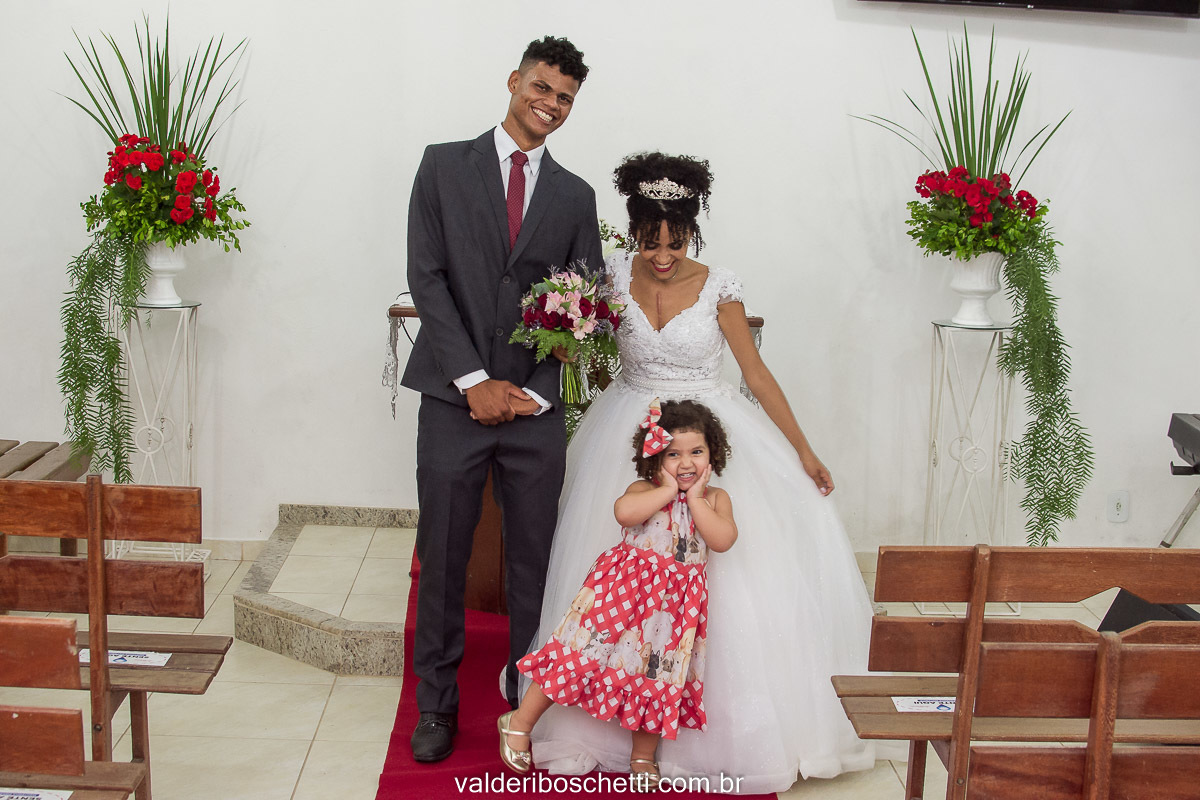 Foto dos noivos e uma criança que estava apaixonada pelo vestido de noiva do casamento realizado na Igreja Maranata em Nova Lidice - Medeiros Neto - BA
Fotografia Valderi Boschetti