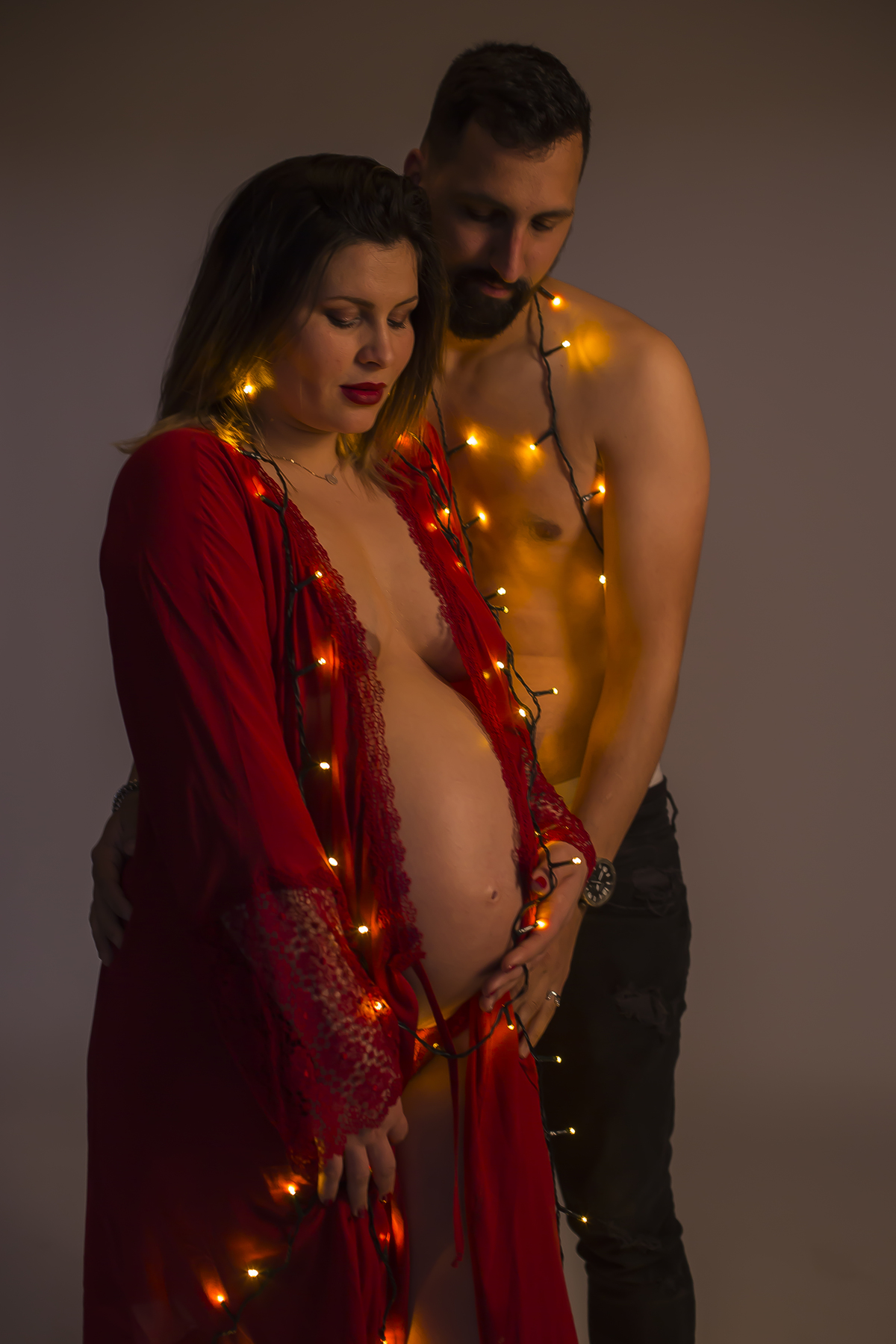 Sessão fotográfica de gravidez com luzes de natal em casal