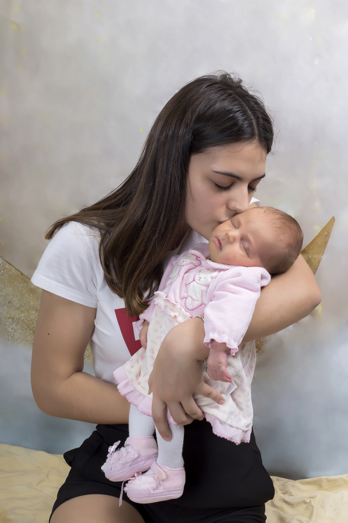 Irmã mais velha a beijar a bebé na sessão fotográfica