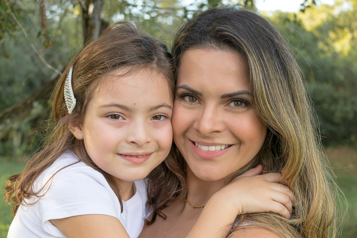 mãe com filha no colo olhando para a camera em um closeup bem próximo