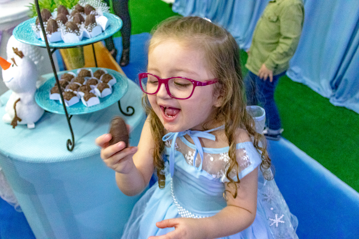 menina de vestido azul olhando para doce e com olhar de louca pra comer