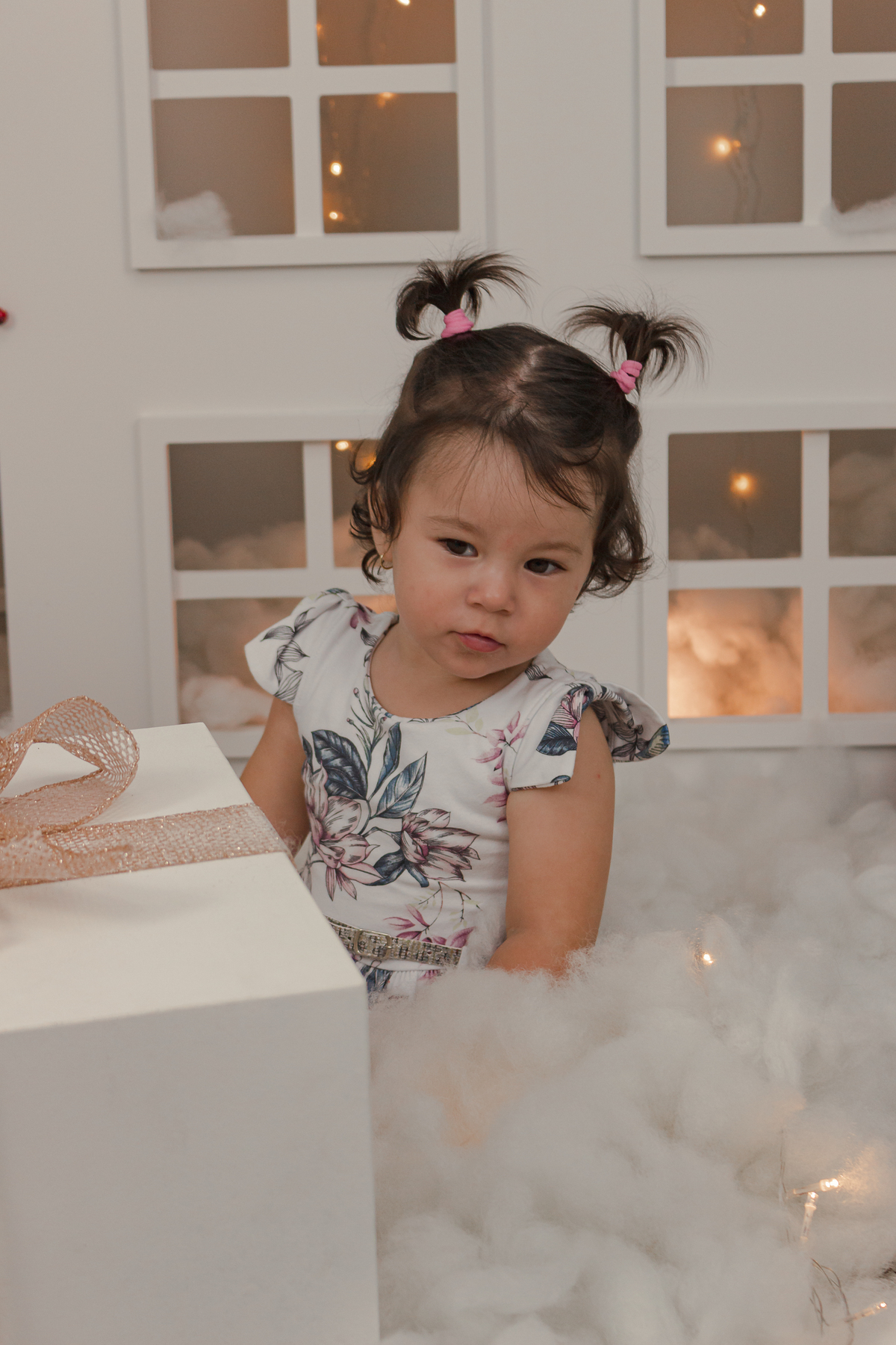 menina atras de um presente de natal e em frente cenario de estudio tema natal