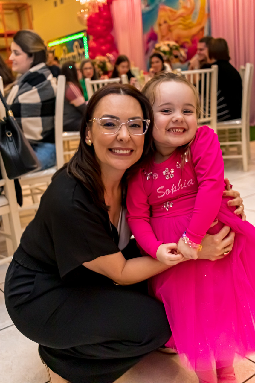 mãe filha abaixadas abraçadas e olhando para a camera