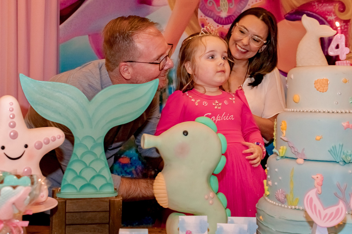 pai,mãe e filha olhando para bolo de aniversário