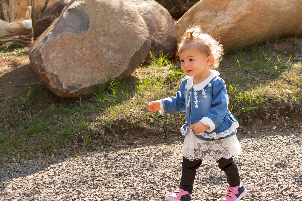 criança correndo no jardim . loirinha cacheada e chuca no cabelo