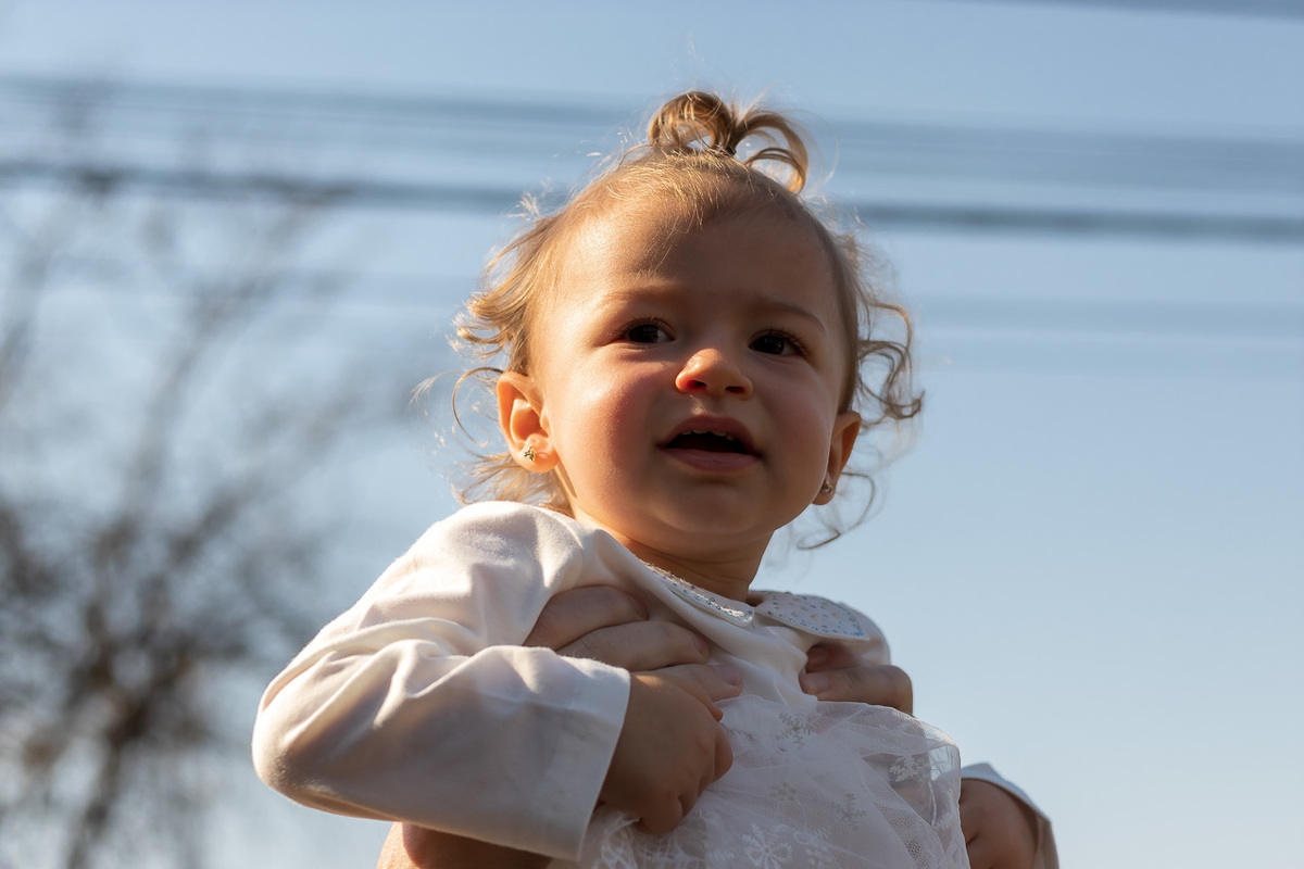 pai segurando a filha por baixo dos braços dela e erguendo