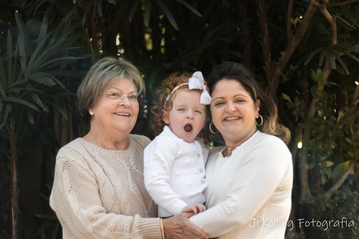 avó filha e neta lado a lado ambas com casacos brancos menininha ruiva no meio bocejando