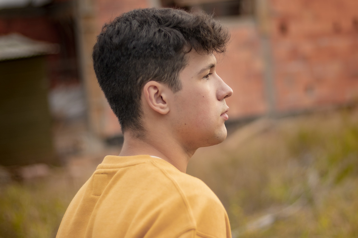 foto de rosto de um garoto de perfil aparecendo somente do ombro para cima. Olhando para o horizonte
