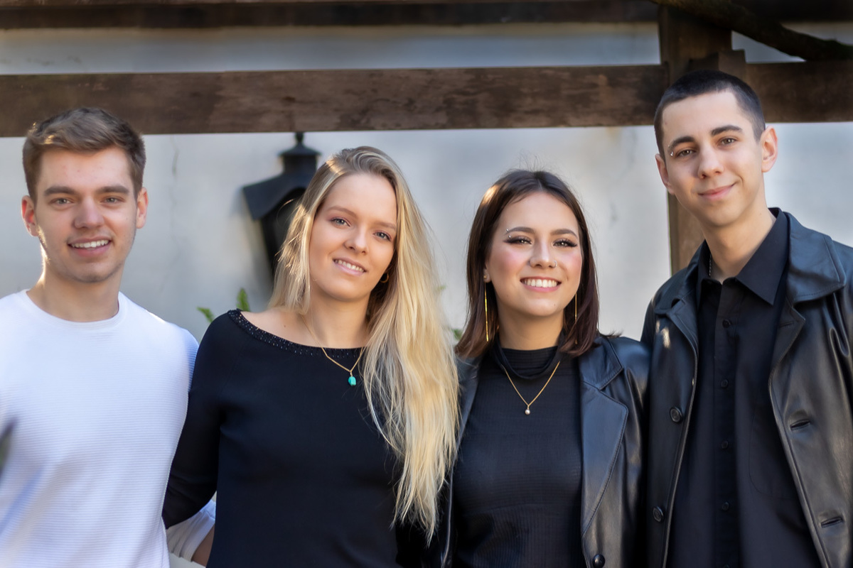fotos de primos. duas garotas no meio e os dois rapazes dos lados. Uma garota loira cabelos compridos caídos no ombro esquerdo e a outra cabelos castanhos na altura dos ombros um dos garotos de preto cabelos curto e o outro de blusa branca cabelo castanho