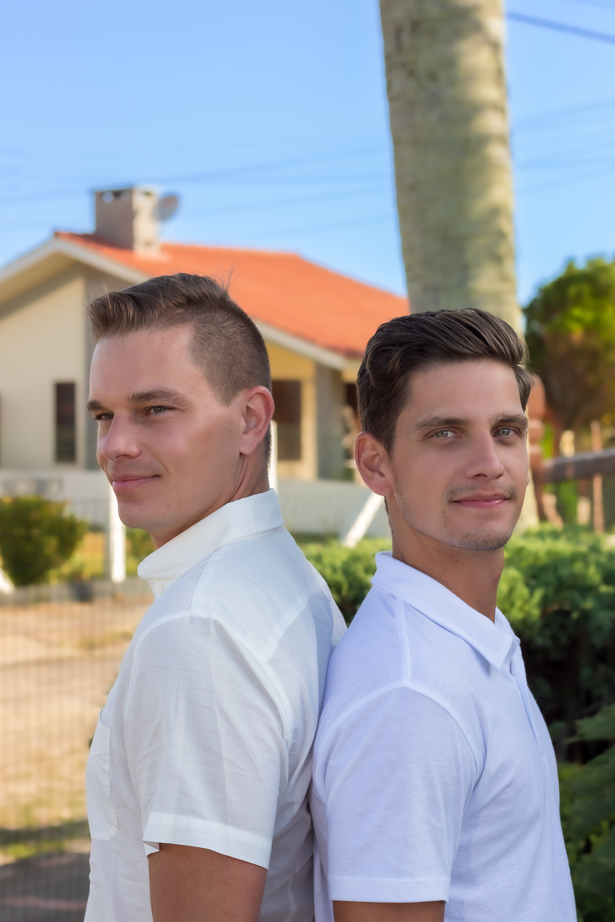 dois rapazes, irmãos, de costas um para o outro olhando para a câmera