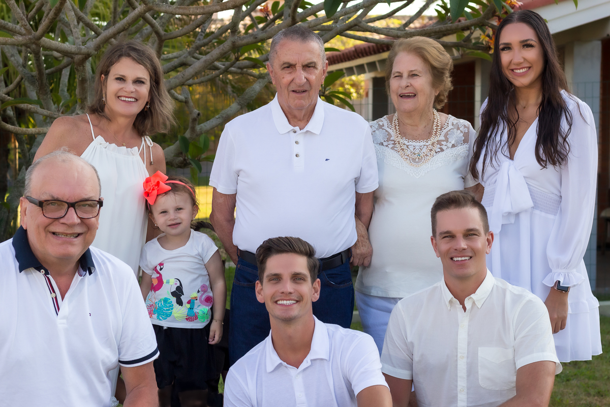 família em duas filas paralelas 3 homens abaixados na frente e atras3 mulheres e o avô. a netinha entre as filas