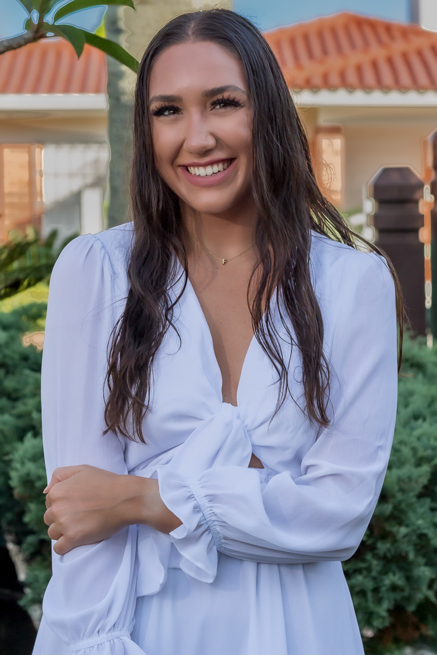 garota com vestido branco sorrindo para a lente cabelos caídos para frente dos ombros