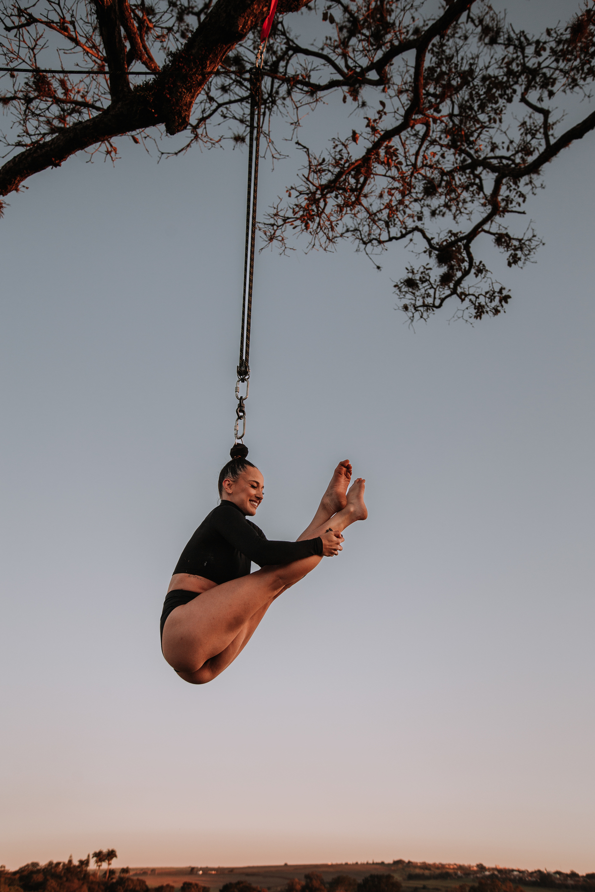 Mulher pendurada pelos cabelos em uma árvore para ser fotografada