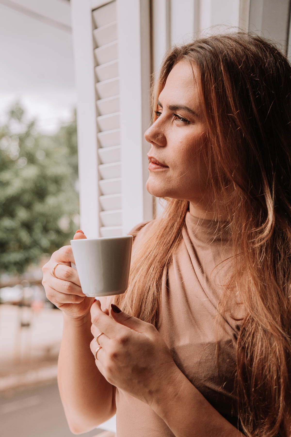 Mulher admirando o tempo com uma xícara de café nas mãos
