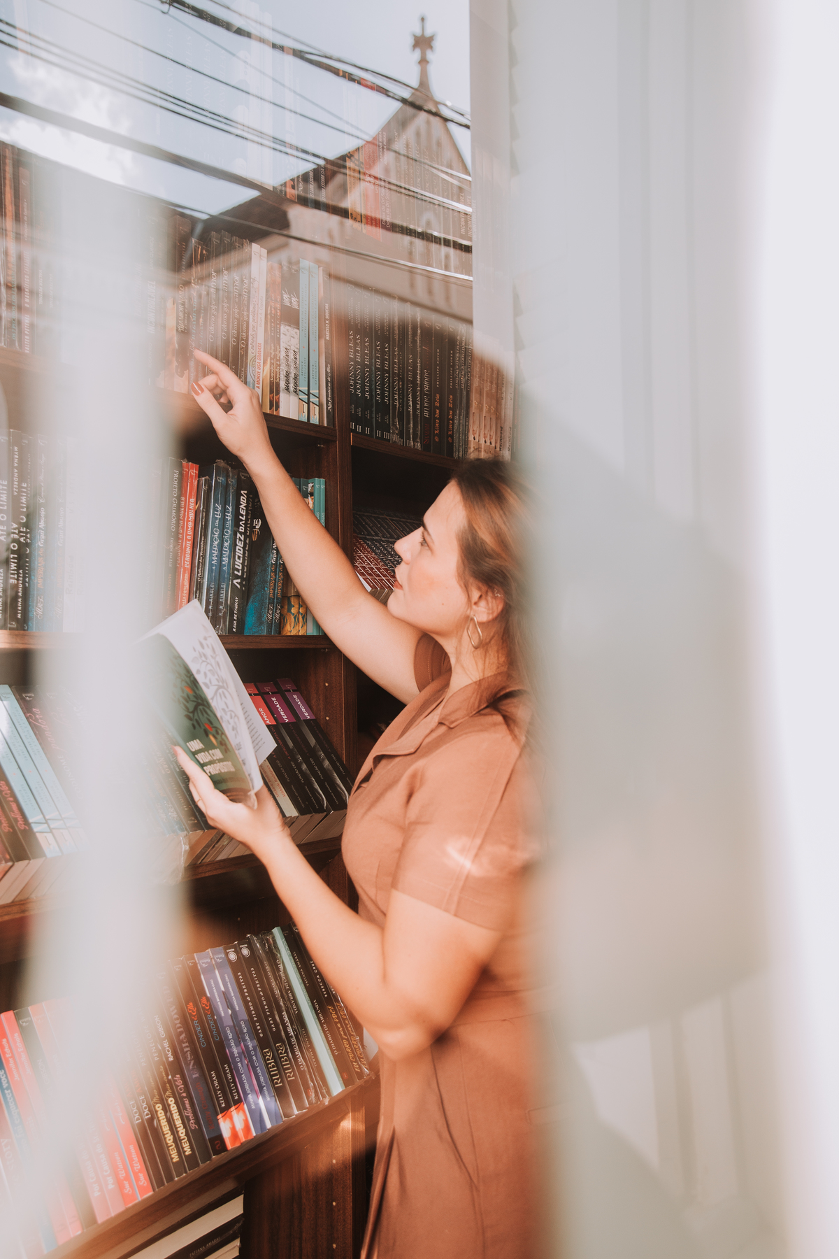 Mulher escolhendo livro em uma livraria no interior de SP