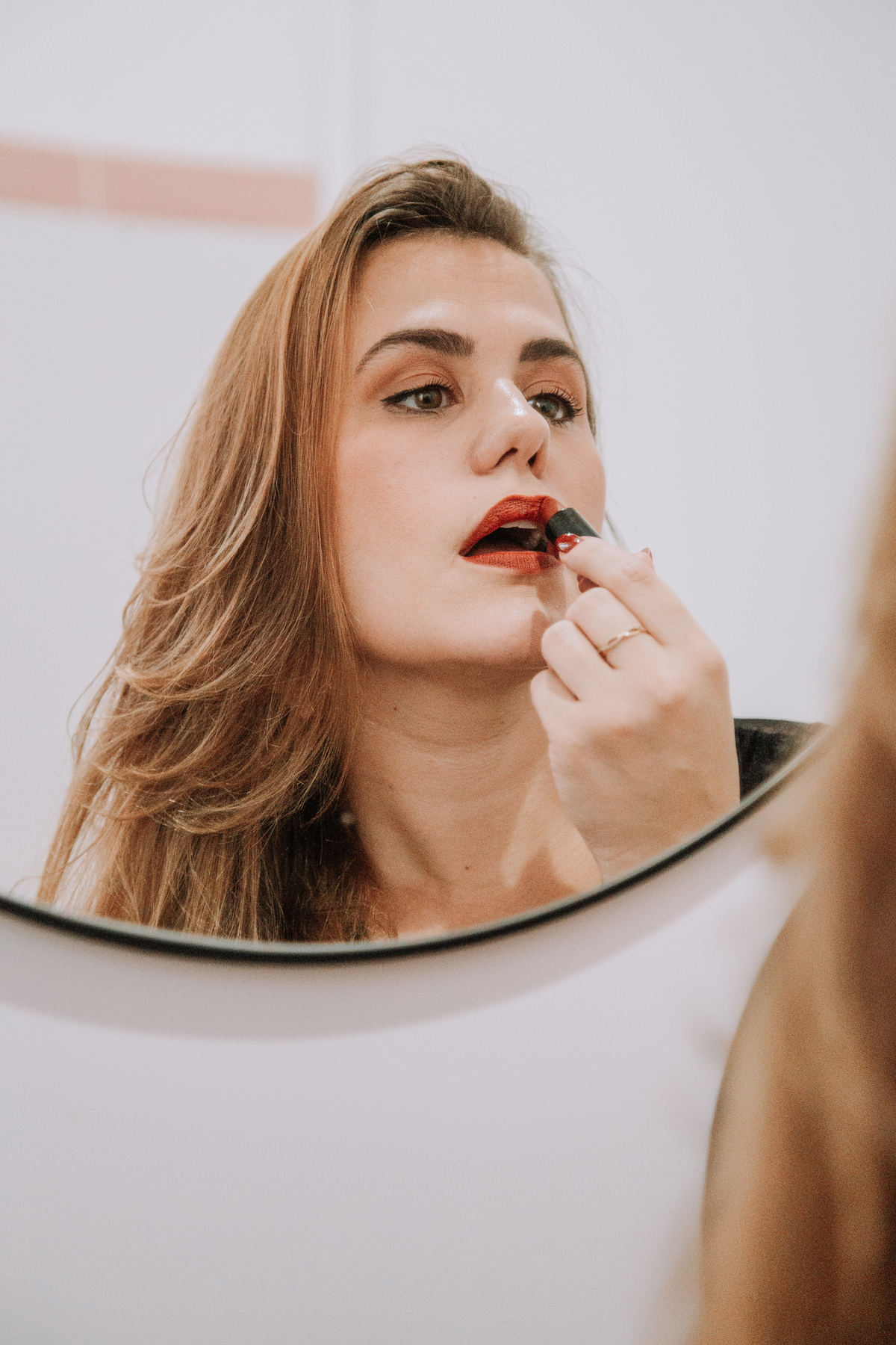 Mulher passando batom vermelho no espelho