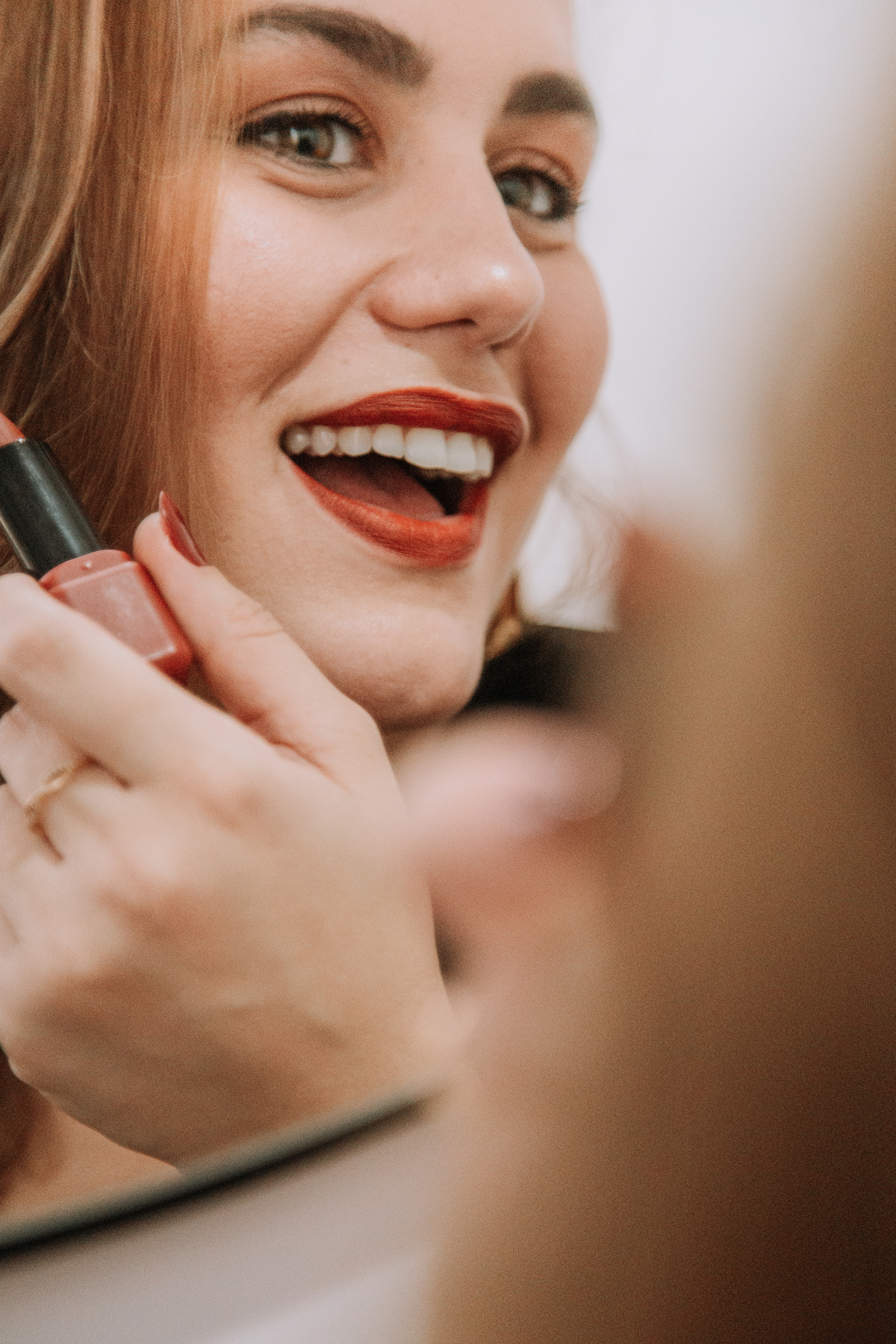 Fotografia de mulher passando batom vermelho no espelho