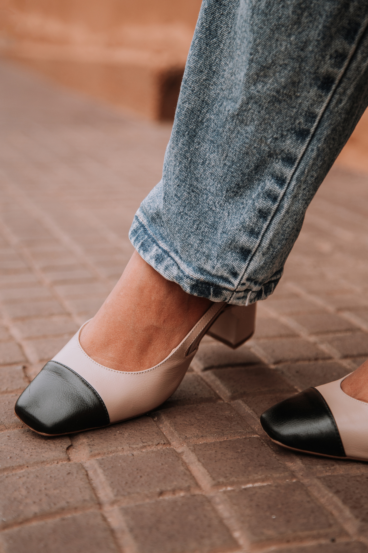 Sapato nude em foco com fundo urbano estético e luz natural suave