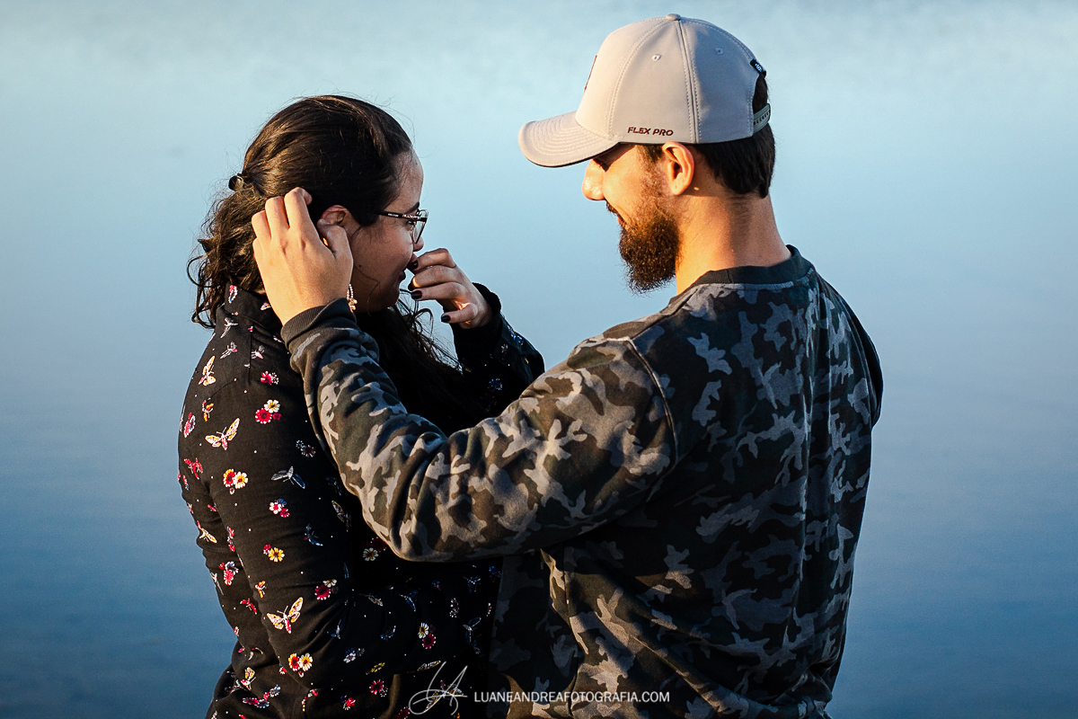 noiva chorando emocionada e noivo olhando para ela em lago no fim de tarde em ensaio pré wedding casamento no campo em taubaté são paulo