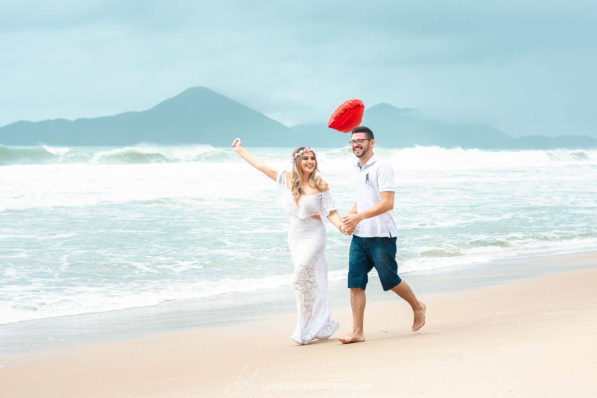 casal correndo na areia com balão de coração em ensaio pré wedding casamento na praia em Ubatuba litoral norte de são paulo