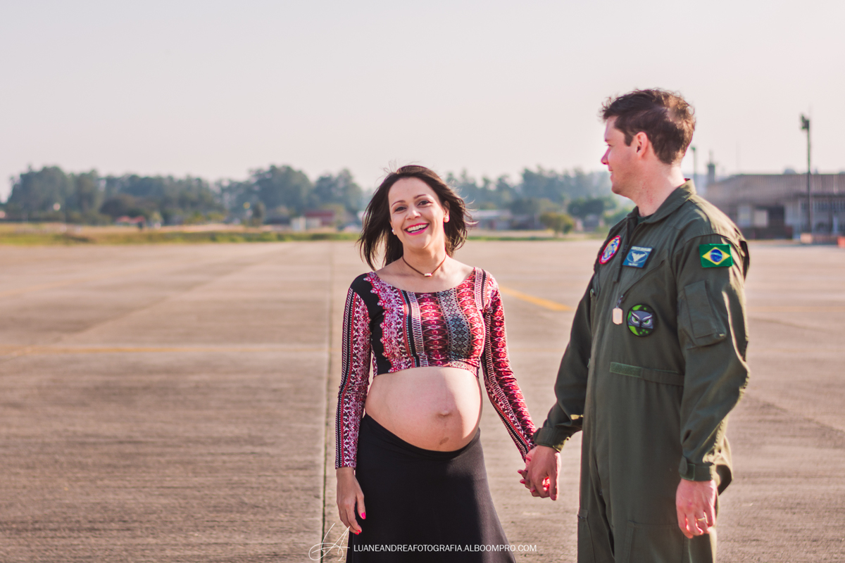 casal se mãos dadas sorrindo em ensaio gestante no helicoptero no bavex em taubaté