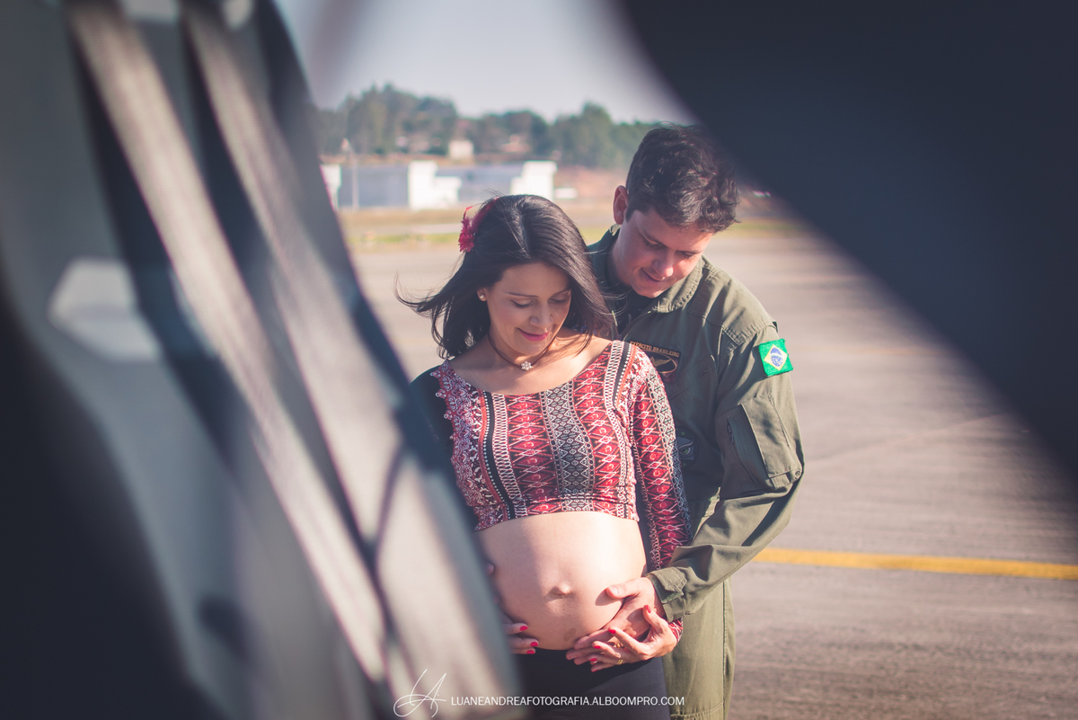 casal olhando para a barriga em ensaio gestante no helicoptero no bavex em taubaté