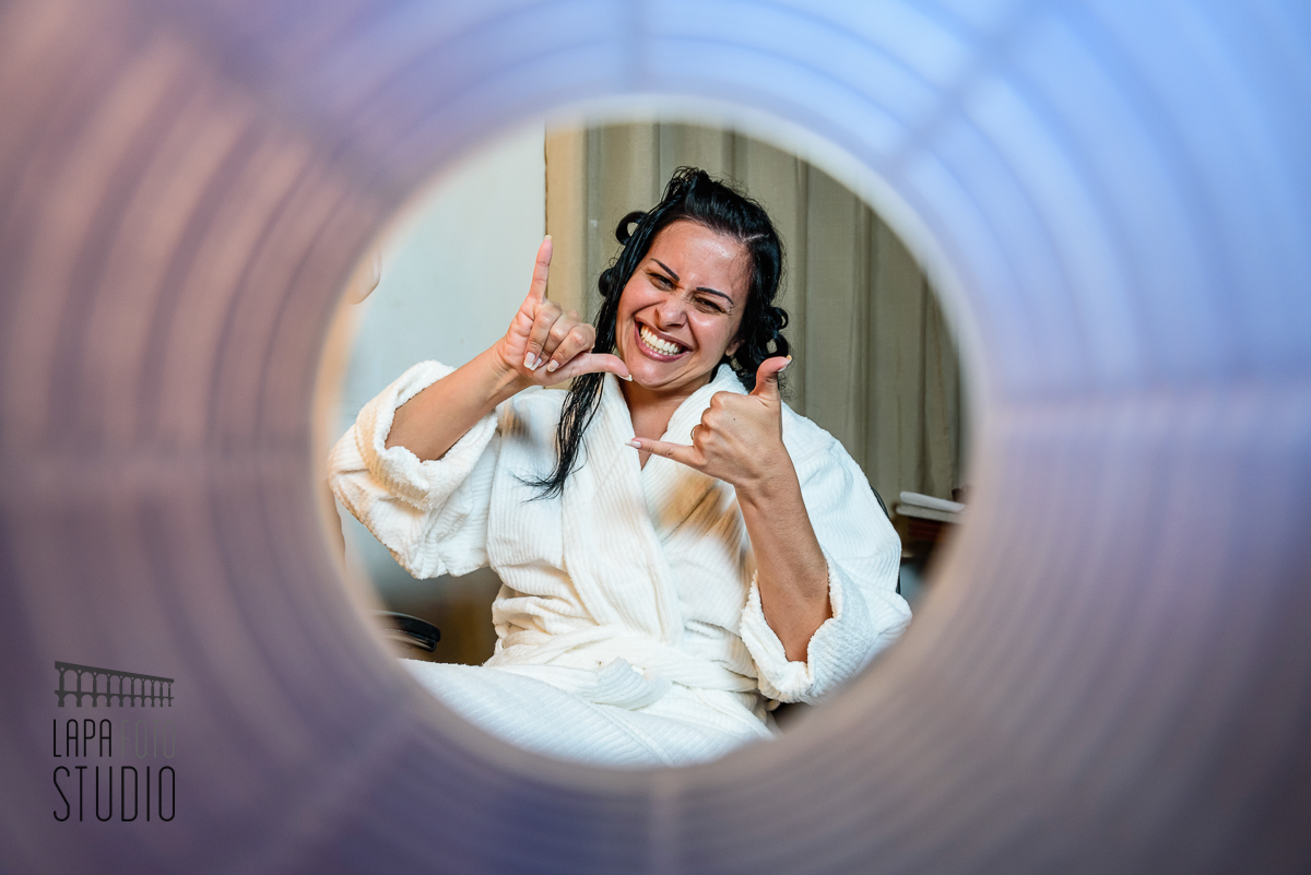 Noiva se divertindo no making of. Foto da noiva através do bob de cabelo.