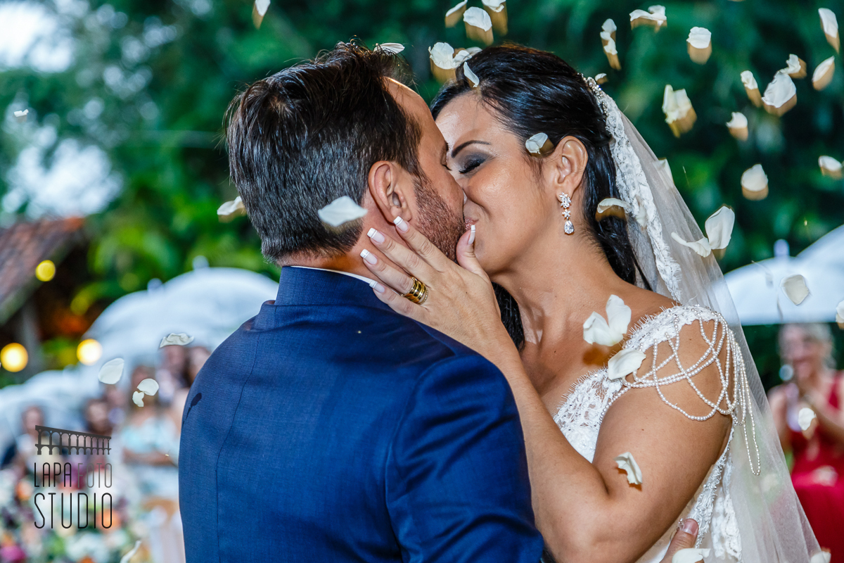 Beijo do casal com pétalas de flor durante a cerimônia no Meio do Mato