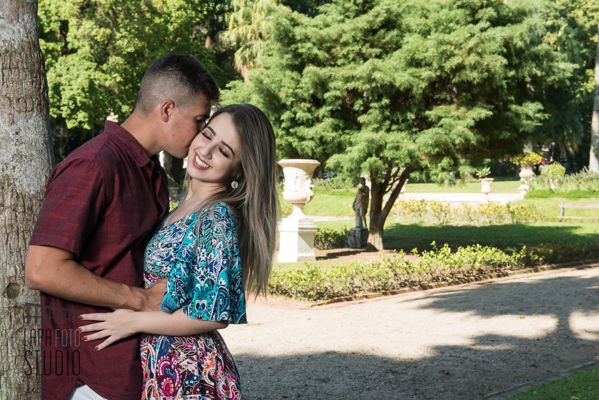 Noivo beija sua noiva encostado numa árvore, no dia do pré wedding no jardim do Palácio Guanabara