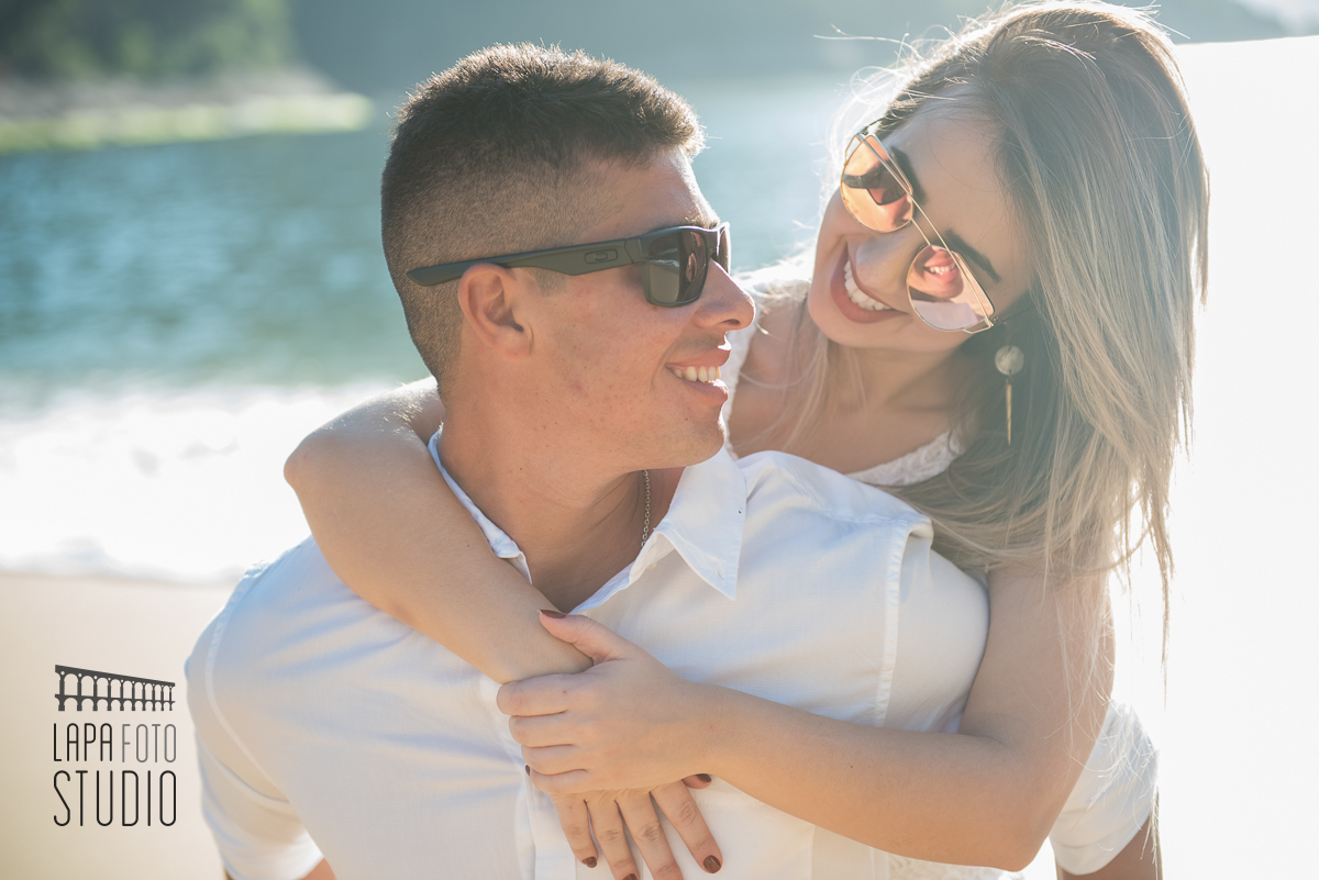 Luz do sol iluminando o casal com olhar apaixonado no dia do pré weddingna praia
