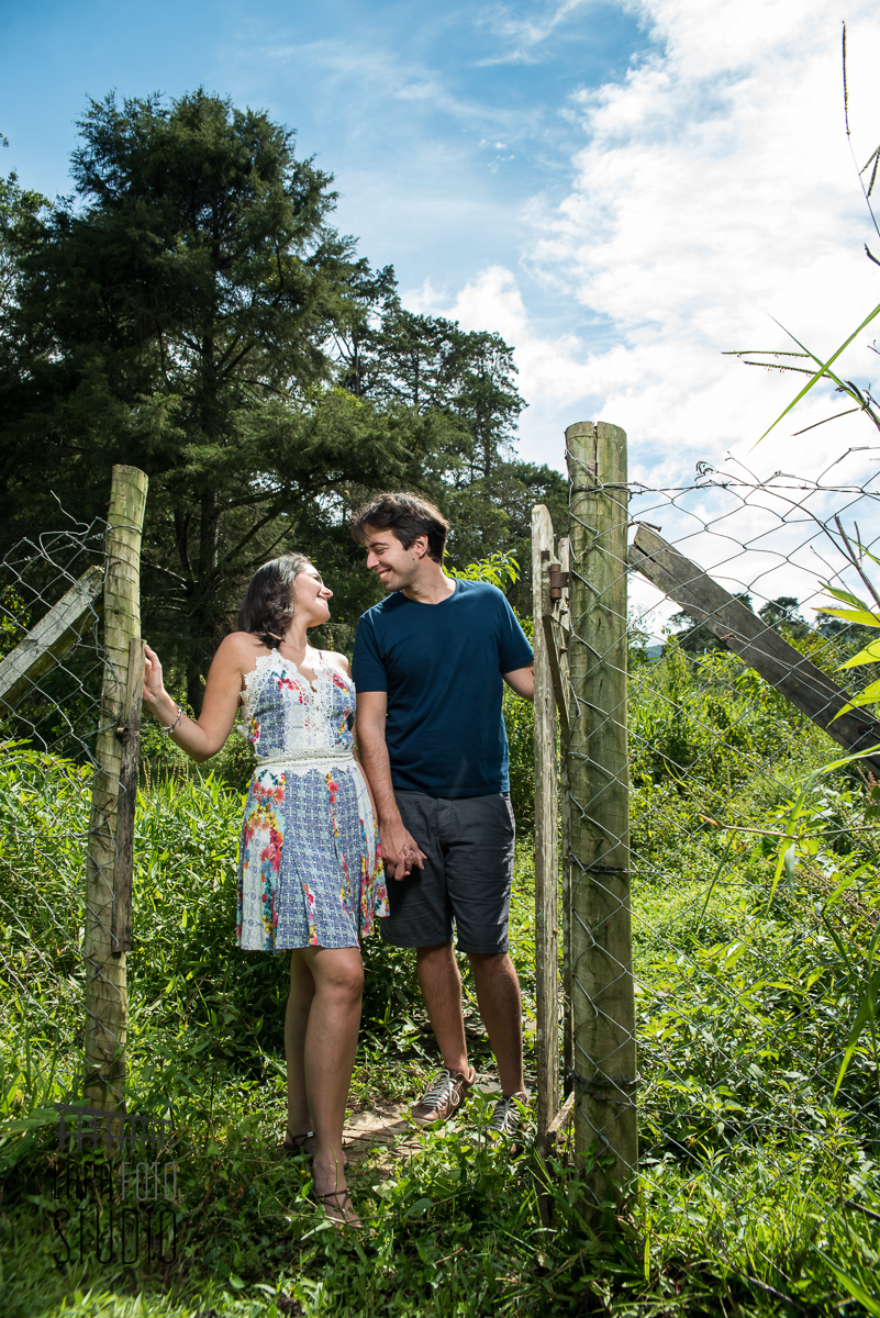 Casal posado na cerca de madeira com clima de fazenda no ensaio pré casamento