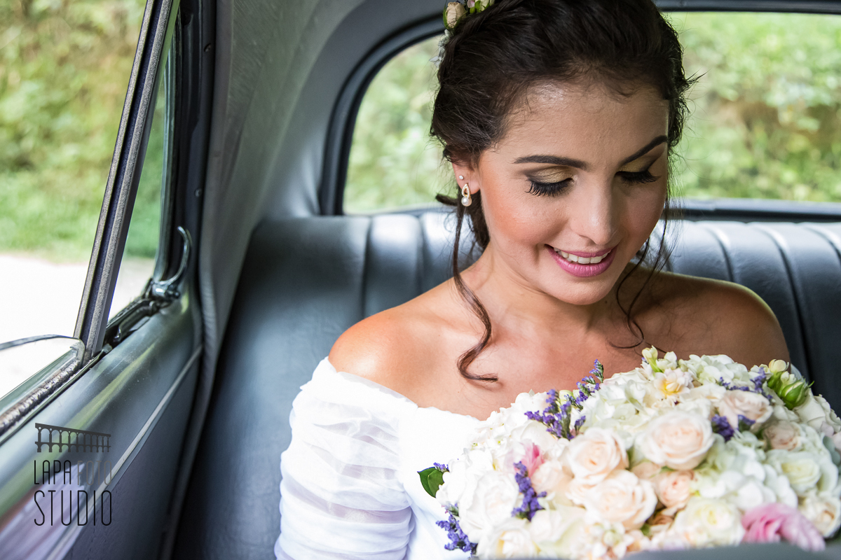 Noiva olhando seu buquê dentro do carro antes do casamento. 