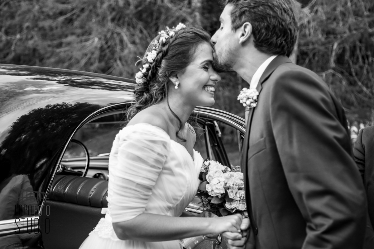 Foto em preto e branco do beijo do irmão na noiva antes da entrada para cerimônia de casamento