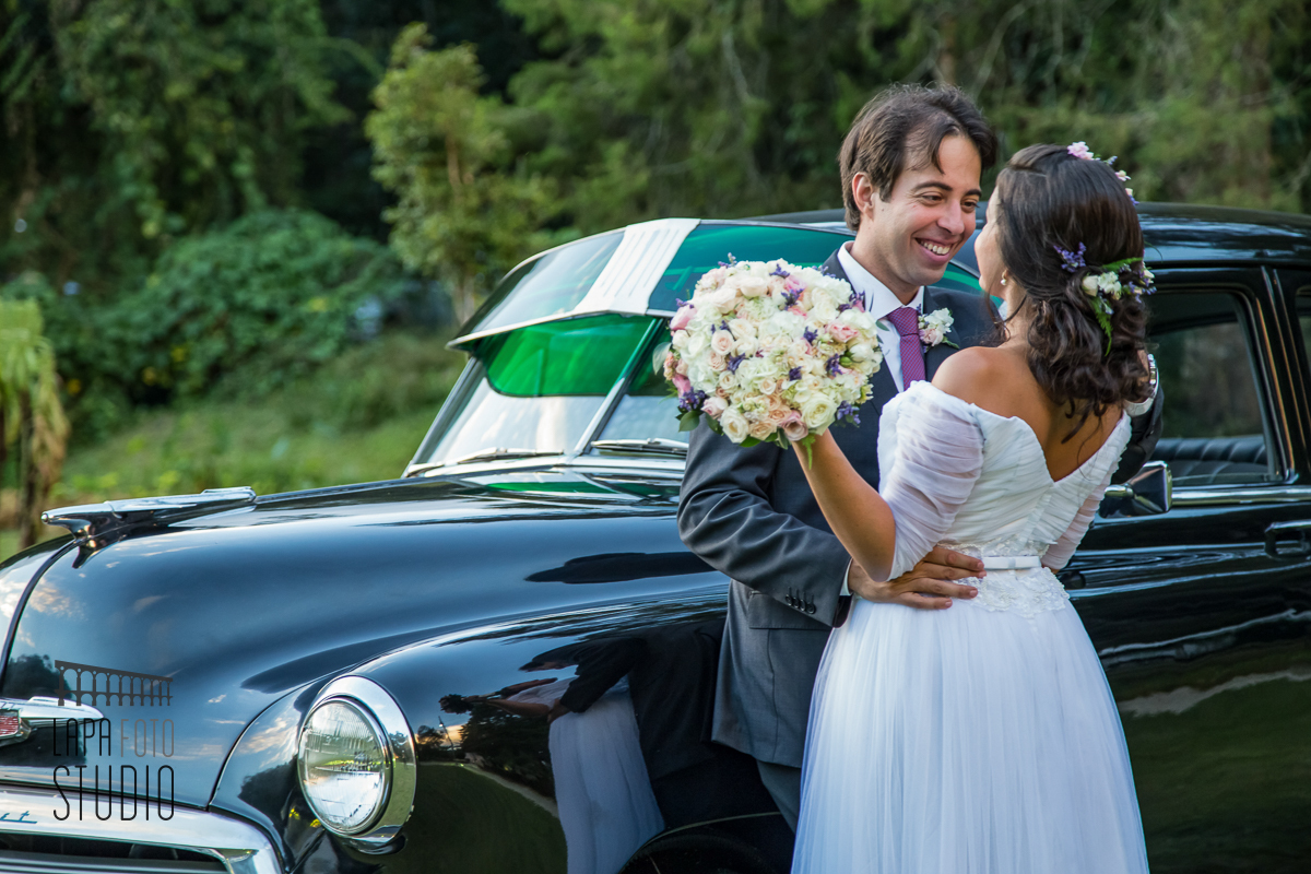 Foto do casal encostado no carro antigo para casamentos, logo após a cerimônia de casamento na região serrana.