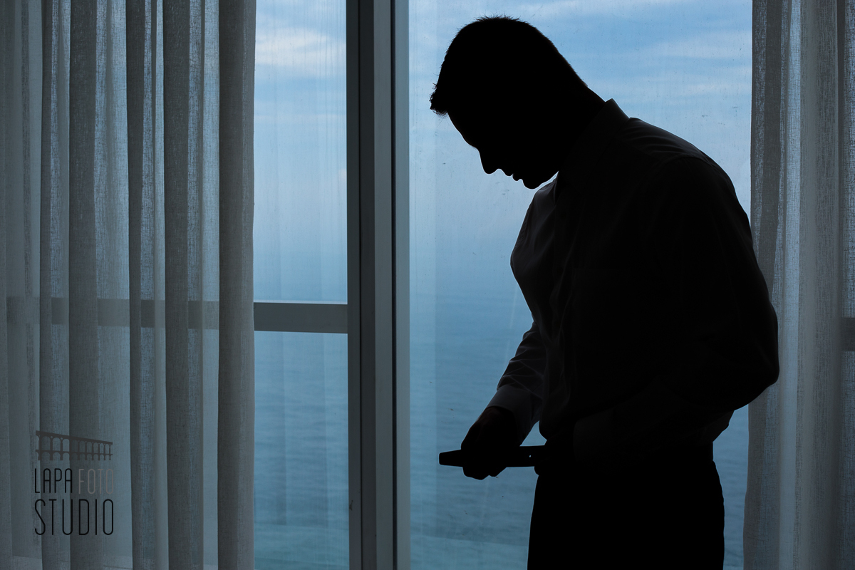 Noivo em contraluz com mar ao fundo na preparação para o casamento