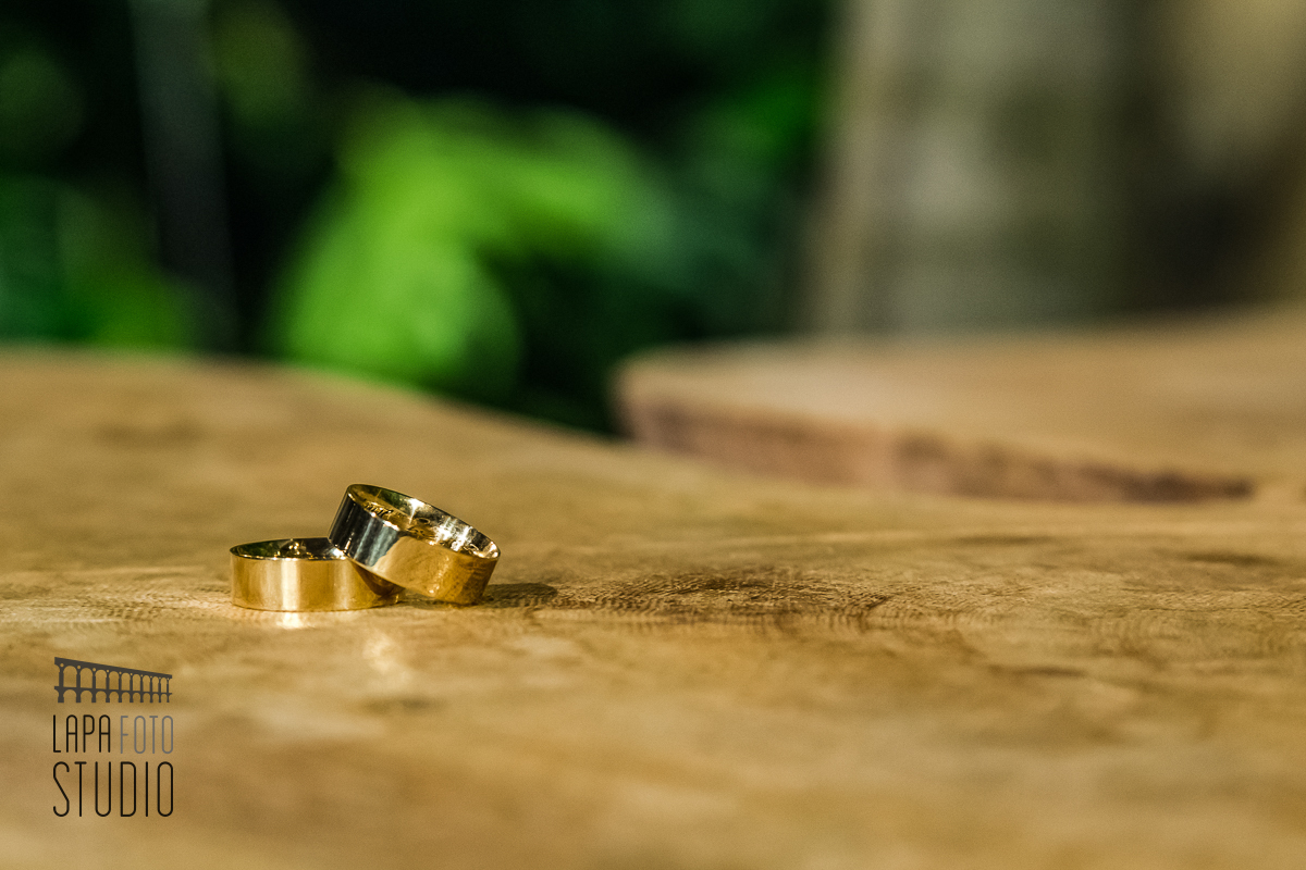 Foto das alianças com iluminação especial em cima da madeira no vale dos sonhos