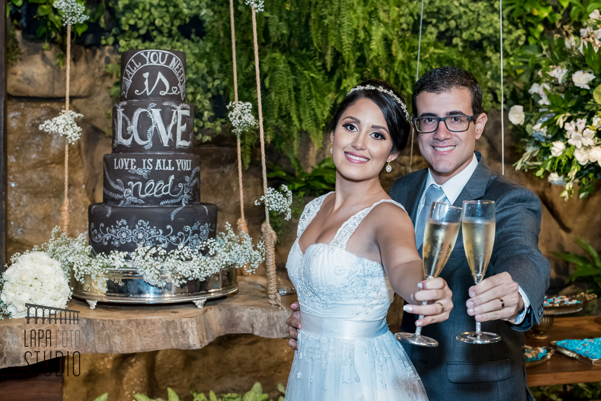 Foto do brinde dos noivos na mesa do bolo durante o casamento